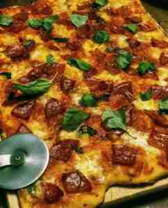 Crusty homemade pizza with fresh basil leaves