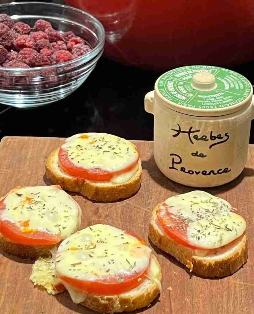 Toasted baquettes slices topped with slices of fresh tomato and fontina cheese, melted and sprinkled with herbs de Provence