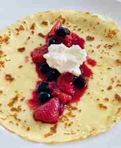 Fruit soup in a crepe with whipped cream