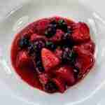 A bowl of fruit soup made with strawberries, bluberries and raspberries easy family dessert